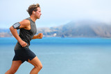 Running app on smartphone. Male runner listening to music jogging with armband for smart phone. Fit man fitness model working outdoor by water.