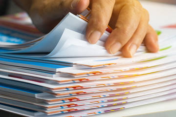 Wall Mural - Businessman hands searching unfinished documents stacks of paper files on office desk for report papers, piles of sheet achieves with clips on table, Document is written, drawn,presented.