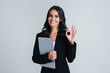 © MARIIA - Perfect working day. Beautiful young businesswoman looking at camera and gesturing OK with smile while standing against white background
