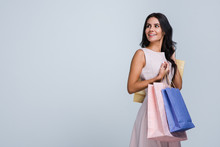 In Love With Shopping. Beautiful Young Woman Holding Shopping Bags And Looking Away With Smile While Standing Against White Background
