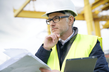 Construction manager on site reading blueprint