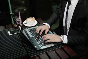 Poster - Young Asian businessman working with a laptop in a coffee shop.