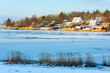 Winter morning landscape of frozen bay and coastal village. Warming sunlight hits the houses on the opposite shore. The bay of Dragsnas outside Ronneby in southern Sweden.