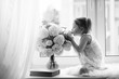 © alexkich - A little girl is sitting on the windowsill. A bouquet of flowers