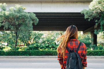 Wall Mural - Young Asian women standing along the street enjoying her city lifestyle in a morning of a weekend waiting for outdoor activity. Young woman and her city lifestyle. city lifestyle and outdoor concept.