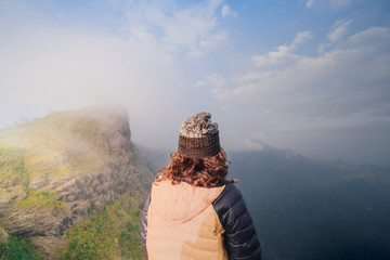 Lovely girl Standing at the back See high peaks, steep brilliant sky spectacular views and fog sprays