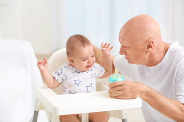 Poster - Senior man giving drink to his little grandchild at home