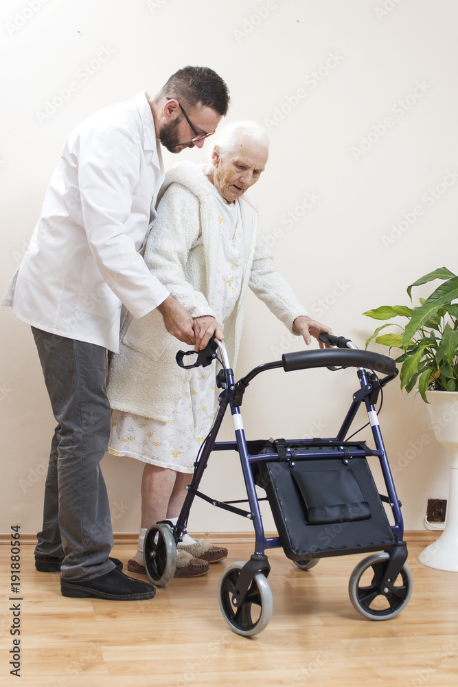 1.	Pielęgniarz pomaga bardzo starej kobiecie iść przy pomocy balkonika rehabilitacyjnego  do chodzenia. - obrazy, fototapety, plakaty 