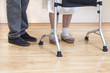 4.	Nogi bardzo starej kobiety w białych skarpetkach i pantoflach. Staruszka uczy się chodzić przy pomocy chodzika rehabilitacyjnego.