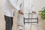 Fototapeta  - Pielęgniarz pomaga bardzo starej kobiecie iść przy pomocy balkonika rehabilitacyjnego  do chodzenia.
