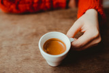 Woman is holding in hand hot coffee espresso in white small glass cup