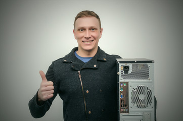 Wall Mural - Happy computer technician man is holding in one hand a computer and is showing on it by his other hand isolated on dark background.