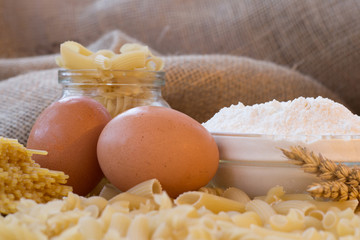 Dry spaghetti pasta tied up with rope and burlap bag of wheat grains