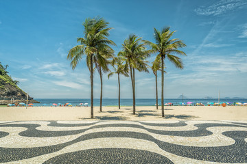 Wall Mural - Palms on Copacabana Beach and landmark mosaic in Rio de Janeiro, Brazil. Sunny day with blue sky