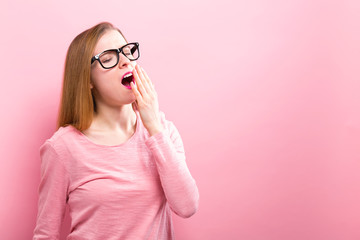 Wall Mural - Young woman yawning on a solid background