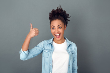 Young african woman isolated on grey wall studio casual daily lifestyle thumb up