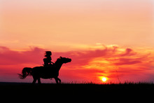 Romantic Pink Sunset With Galloping Horse And Female Silhouette. Horseback Riding On Rising Sun Horizon. Arabian Horse Safari On Colorful Sunset Background. 