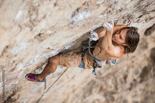 Fotomural shirtless male climber working hard to lead up a rock wall