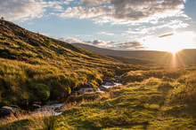 Beautiful, Cloudy Sunset Over A Small River Flowing Through Green, Grass Covered Hills In Wicklow Mountains, Ireland