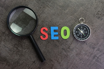 Aufkleber - magnifier glass, colorful alphabet seo and compass on dark chalkboard background using as seo search