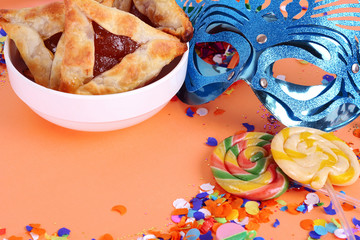 Purim background with carnival mask, party costume and hamantaschen cookies.