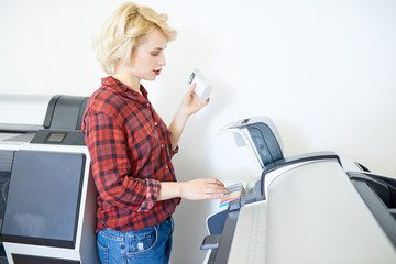 Fototapete - Side view portrait of modern young woman loading printers with ink in publishing company, copy space