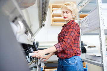 Fototapete - Side view portrait of modern blonde woman working with plotters in printing shop of publishing company