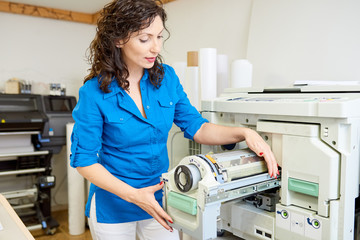 Fototapete - Portrait of woman changing paper roll in multi functional office machine in printing shop