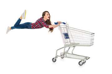 Wall Mural - young woman levitating with empty shopping trolley isolated on white