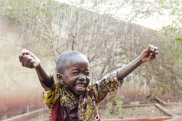 water is coming! african ethnicity little boy happy to finally get some rain