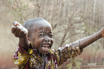 little native african boy standing outdoors under the rain (water for africa symbol)