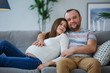 © Sergey Mironov - Photo of happy pregnant woman and man on gray sofa