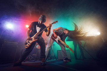 Wall Mural - Rock band performs on stage. Guitarist, bass guitar and drums.