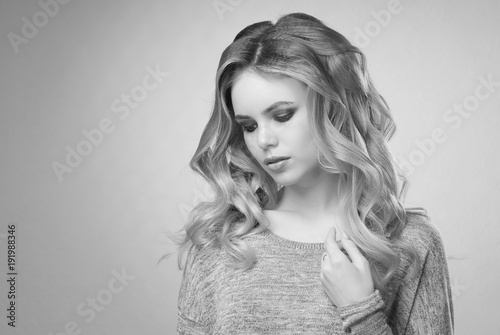 Blonde Girl In A Gray Sweater With Long Curled Hair And Makeup