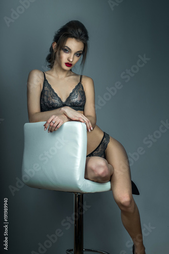 Fotografia gorgeous woman with red lips and beautiful hairstyle sits on white leather chair