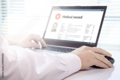 Cuadros en Lienzo Doctor using laptop and electronic medical record (EMR) system