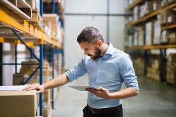 Poster - Man warehouse worker with a tablet.