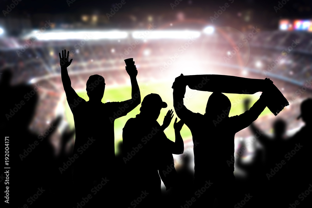 Siluet fans sepak bola merayakan gol di stadion malam hari