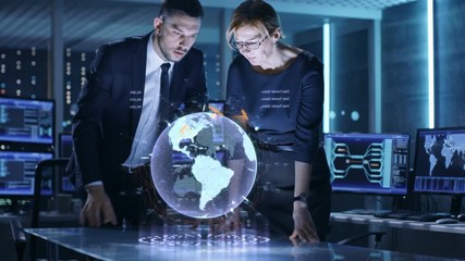 Poster - Male and Female Agents Use Mixed Media Holographic Table for Satellite Surveillance. In the Monitoring Room of Special International Security Unit Tracking Targets.