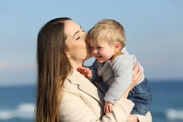 Wall Mural - Mother kissing her kid son outdoors