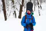 Happy snowboarder stands in the winter forest