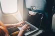 © MZaitsev - young red-haired woman uses laptop while flying on airplane near window, close-up