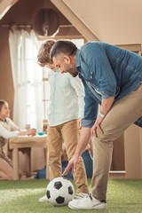 Wall Mural - happy father teaching his som to play soccer on grass