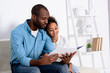 © LIGHTFIELD STUDIOS - african american father reading book to daughter at home