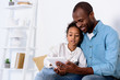 © LIGHTFIELD STUDIOS - african american father and daughter watching something on tablet at home