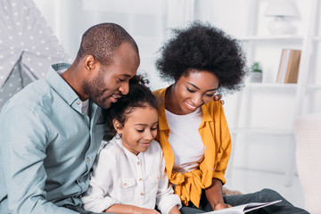 Wall Mural - african american parents reading with daughter at home