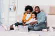 © LIGHTFIELD STUDIOS - african american parents and daughter watching movie on laptop at home