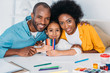 © LIGHTFIELD STUDIOS - african american parents and daughter with felt pens looking at camera at home