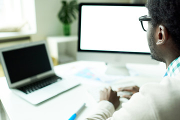 Side view of African-American IT specialists working in web studio coding on two computers, copy space