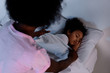 © LIGHTFIELD STUDIOS - african american mother covering sleeping daughter with blanket at home